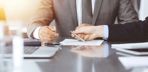 Bilinmeyen iş adamları modern ofiste birlikte çalışıyorlar, yakın plan. İş adamı ve kadın iş arkadaşları veya avukatlarıyla pazarlıkta sözleşmeyi tartışıyor