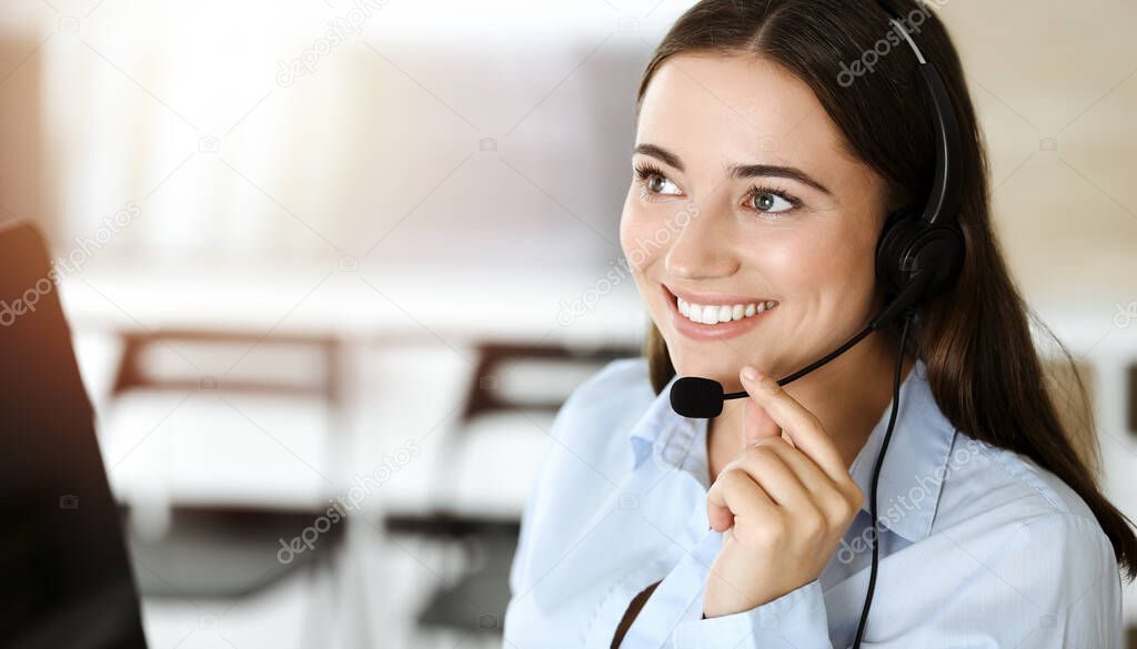 Brunette female customer service representative using headset and consulting clients online. Call center