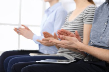 İş adamları toplantı ya da konferansta el çırpıyor. Modern beyaz ofisteki bir grup tanınmayan iş adamı ve kadın. Başarı takım çalışması, kurumsal koçluk ve alkış konsepti