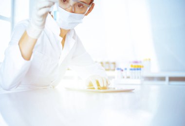 Kadın laboratuvar asistanı mavi sıvıyla test tüpünü analiz ediyor. Tıp, sağlık ve araştırma konsepti