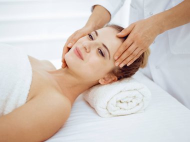 Genç ve sarışın kadın spa salonunda yüz masajından zevk alıyor. Güzellik konsepti