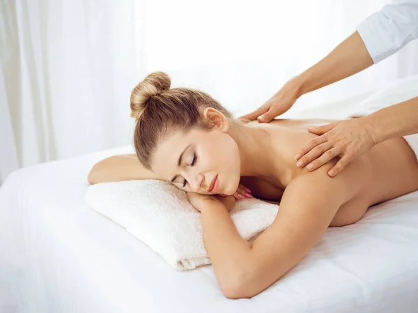 Ung och blond kvinna njuter av massage av tillbaka i spa salong. Skönhetsbegreppet — Stockfoto