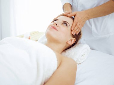 Genç ve sarışın kadın spa salonunda yüz masajından zevk alıyor. Güzellik konsepti