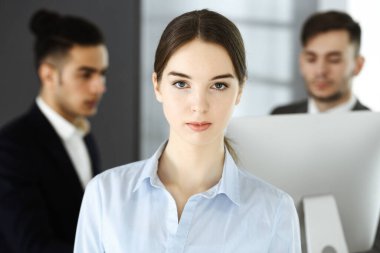 Modern ofisin arka planında iş kadını ve çeşitli iş adamları var. Çok ırklı takım çalışması ve iş konsepti