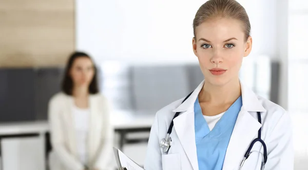 Mujer - médico está utilizando portapapeles para llenar el formulario de registro de historial de medicamentos en la clínica en el fondo de la paciente. Concepto de medicina — Foto de Stock