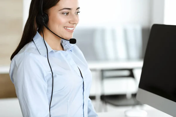 Morena representante de servicio al cliente femenino en un auricular está consultando a los clientes en línea. Centro de llamadas y concepto de gente de negocios — Foto de Stock