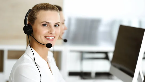 Bionda rappresentante del servizio clienti femminile e la sua collega stanno consultando i clienti online utilizzando cuffie. Call center e business people concept — Foto Stock