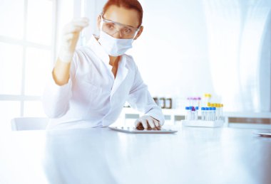 Kadın laboratuvar asistanı mavi sıvıyla test tüpünü analiz ediyor. Tıp, sağlık ve araştırma konsepti