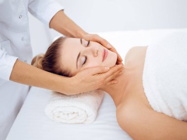 Genç ve sarışın kadın spa salonunda yüz masajından zevk alıyor. Güzellik konsepti