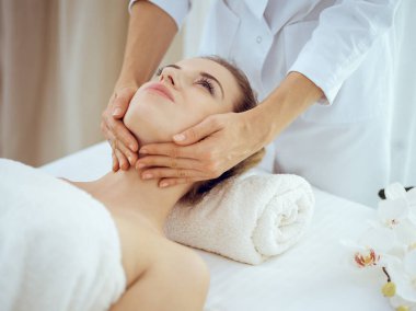 Genç ve sarışın kadın spa salonunda yüz masajından zevk alıyor. Güzellik konsepti