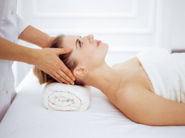 Genç ve sarışın kadın spa salonunda yüz masajından zevk alıyor. Güzellik konsepti
