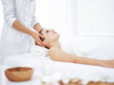 Genç ve sarışın kadın spa salonunda yüz masajından zevk alıyor. Güzellik konsepti