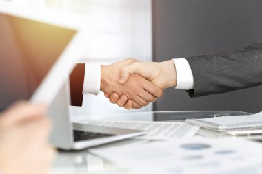 Bilinmeyen çeşitli iş adamları, güneşli ofiste sözleşme imzalarken el sıkışıyorlar. İş tokalaşma kavramı