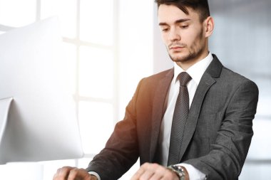 Güneşli ofiste bilgisayarla çalışan bir iş adamı. İş yerindeki erkek girişimcinin vesikalığı. İş konsepti