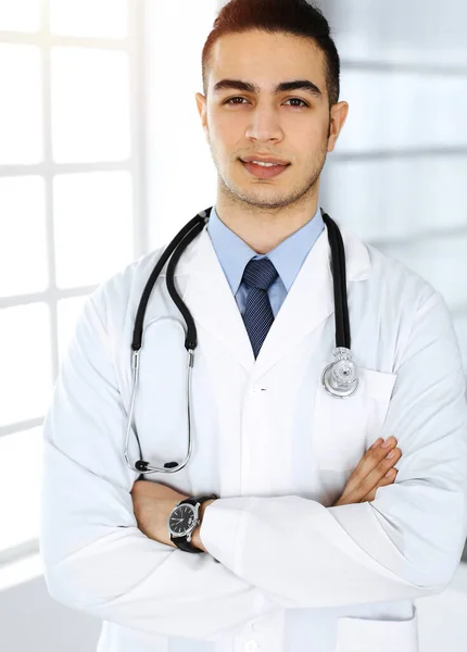 O médico árabe está de pé com os braços cruzados na clínica. Conceito de medicina e saúde — Fotografia de Stock