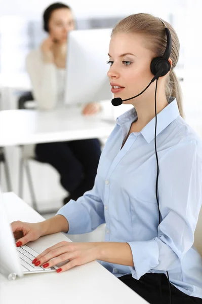 Blond woman call operator is using computer and headset for consulting clients online. Group of diverse people working as customer service occupation. Business concept — Stock Photo, Image