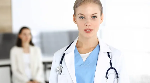 Mujer - médico de pie en la clínica. Médico en el trabajo, retrato de estudio. Concepto de medicina y salud —  Fotos de Stock