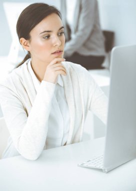 Ofiste bilgisayarla çalışan sıradan giyinmiş bir iş kadını. İş yerinde avukat ya da muhasebeci