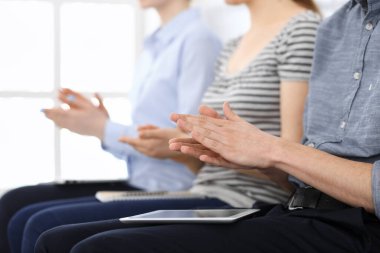 İş adamları toplantı ya da konferansta el çırpıyor. Modern beyaz ofisteki bir grup tanınmayan iş adamı ve kadın. Başarı takım çalışması, kurumsal koçluk ve alkış konsepti