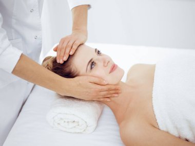Genç ve sarışın kadın spa salonunda yüz masajından zevk alıyor. Güzellik konsepti