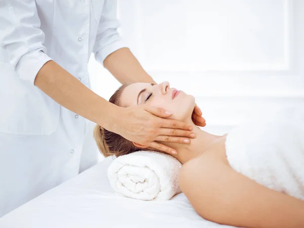 Mulher jovem e loira desfrutando de massagem facial no salão de spa. Conceito de beleza — Fotografia de Stock
