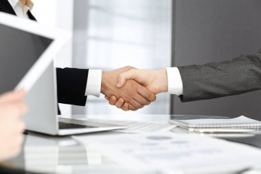 Bilinmeyen çeşitli iş adamları ofis masasındaki toplantıyı bitirmek için el sıkışıyorlar, yakın plan. El sıkışma kavramı
