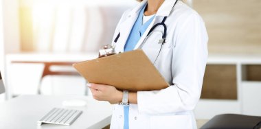 Güneşli klinikte bilinmeyen bir kadın doktor. Kadın doktor tıbbi geçmişi kontrol ediyor, yakın plan. Tıp konsepti