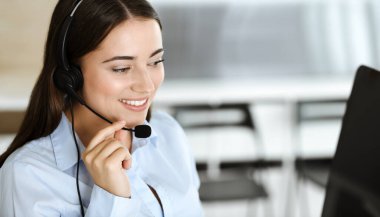 Esmer kadın müşteri hizmetleri temsilcisi internet üzerinden müşterilere danışıyor. Çağrı merkezi ve iş adamları kavramı