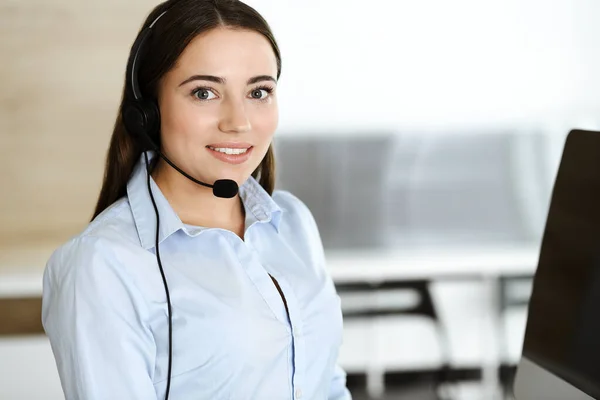 Brunette representante de atendimento ao cliente do sexo feminino em um fone de ouvido está consultando clientes on-line. Call center e conceito de pessoas de negócios — Fotografia de Stock