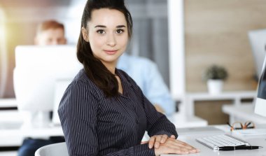 İş kadını, güneşli ofiste bilgisayar kullanıyor. Zevk ve başarı için çalışmak