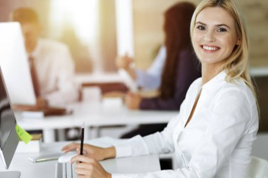 İş yerinde bilgisayarını kullanan sarışın bir iş kadını. Zevk ve başarı için çalışmak