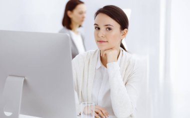 Ofiste bilgisayarla çalışan sıradan giyinmiş bir iş kadını. İş yerinde avukat ya da muhasebeci