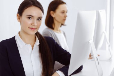 İş kadını, çalışan iş arkadaşlarının arka planına bakıyor. Ofis hayatı konsepti, vesikalık