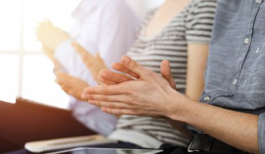 İş adamları toplantı ya da konferansta el çırpıyor. Kimliği belirsiz işadamları ve kadınlar güneşli ofiste.