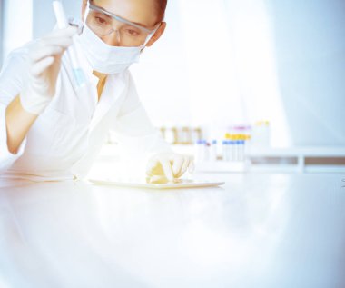 Kadın laboratuvar asistanı mavi sıvıyla test tüpünü analiz ediyor. Tıp, sağlık ve araştırma konsepti