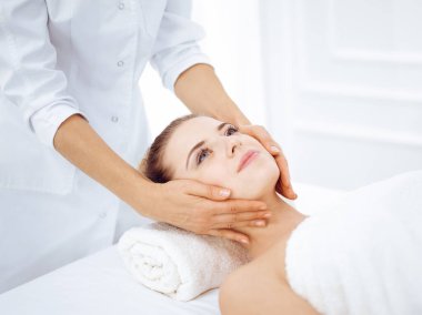 Genç ve sarışın kadın spa salonunda yüz masajından zevk alıyor. Güzellik konsepti