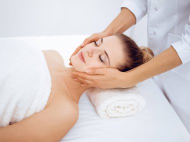 Genç ve sarışın kadın spa salonunda yüz masajından zevk alıyor. Güzellik konsepti