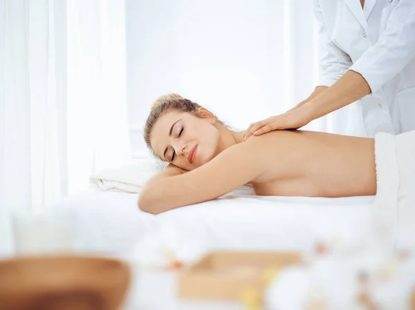 Ung och blond kvinna njuter av massage av tillbaka i spa salong. Skönhetsbegreppet — Stockfoto