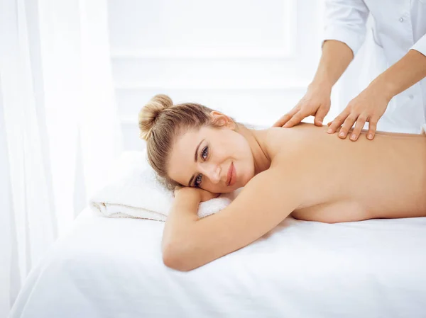Ung och blond kvinna njuter av massage av tillbaka i spa salong. Skönhetsbegreppet — Stockfoto