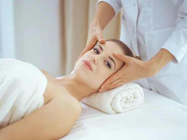 Jonge en blonde vrouw geniet van gezichtsmassage in spa salon. Schoonheidsconcept — Stockfoto