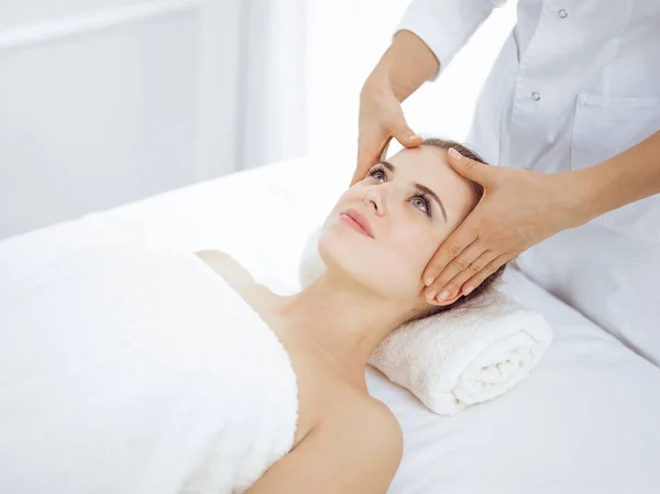 Young and blonde woman enjoying facial massage in spa salon. Beauty concept — Stock Photo, Image