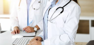 Bilinmeyen kadın doktor güneşli klinikteki resepsiyonda masaüstü bilgisayarında daktilo yazıyor. Tıp konsepti