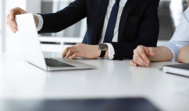 Bilinmeyen iş adamları modern ofisteki masada dizüstü bilgisayar kullanıyorlar. İş adamı ya da erkek girişimci meslektaşı ile birlikte çalışıyor. Takım çalışması ve ortaklık kavramı