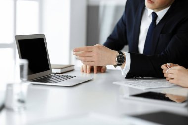 Meçhul iş adamları ve kadınlar modern ofiste oturuyorlar, çalışıyorlar ve sorularını tartışıyorlar.