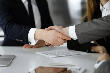Bilinmeyen işadamı, modern ofiste iş arkadaşı ya da ortağıyla el sıkışıyor. Toplantıda iş adamları grubu
