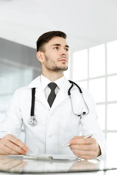 Dokter man vullen medicatie geschiedenis administratie formulier tijdens het zitten aan het glazen bureau in kliniek. Concept geneeskunde en gezondheidszorg — Stockfoto