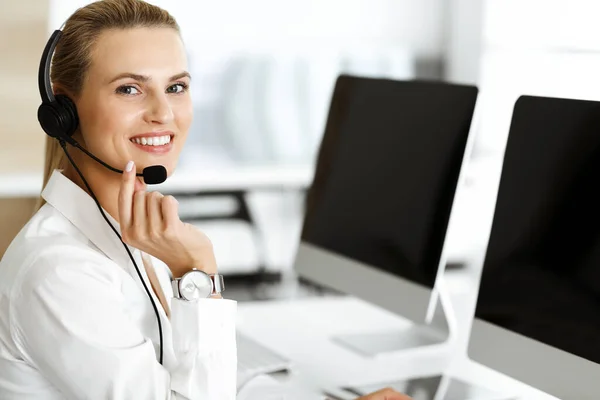 Il rappresentante del servizio clienti femminile biondo sta consultando i clienti online utilizzando le cuffie. Call center e business concept — Foto Stock