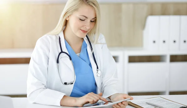Mujer-médico sentado en la clínica soleada y el uso de la tableta PC. Datos y mejor servicio en medicina y salud — Foto de Stock