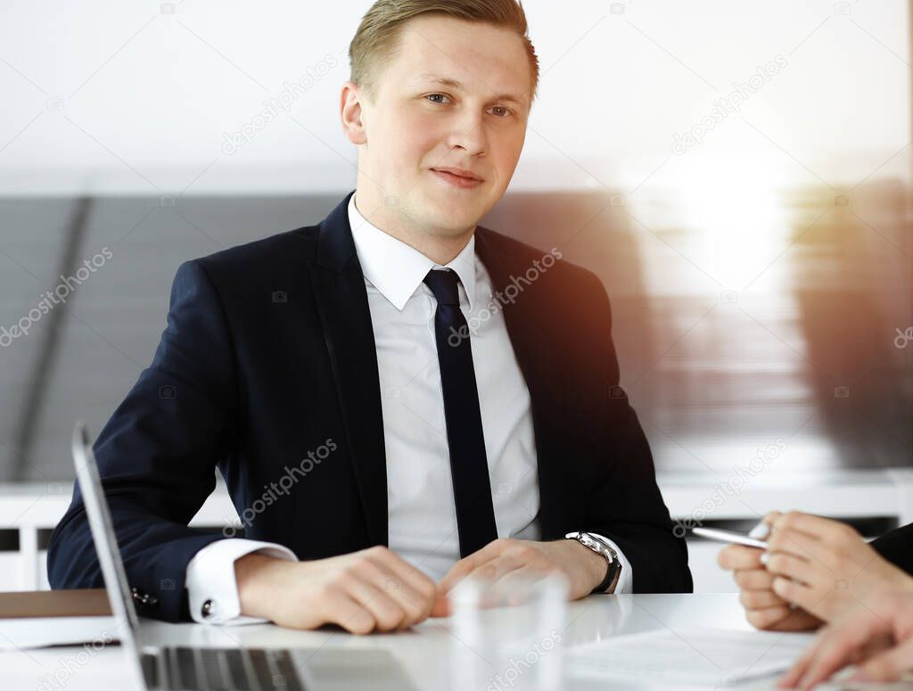 Businessman at meeting in sunny office. Entrepreneur sitting with his colleagues at the desk