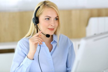 Merkezi ara. Müşteri hizmetleri ofisinde kulaklık takan sarışın bir iş kadını. Telesellerin iş ya da ev işgali kavramı